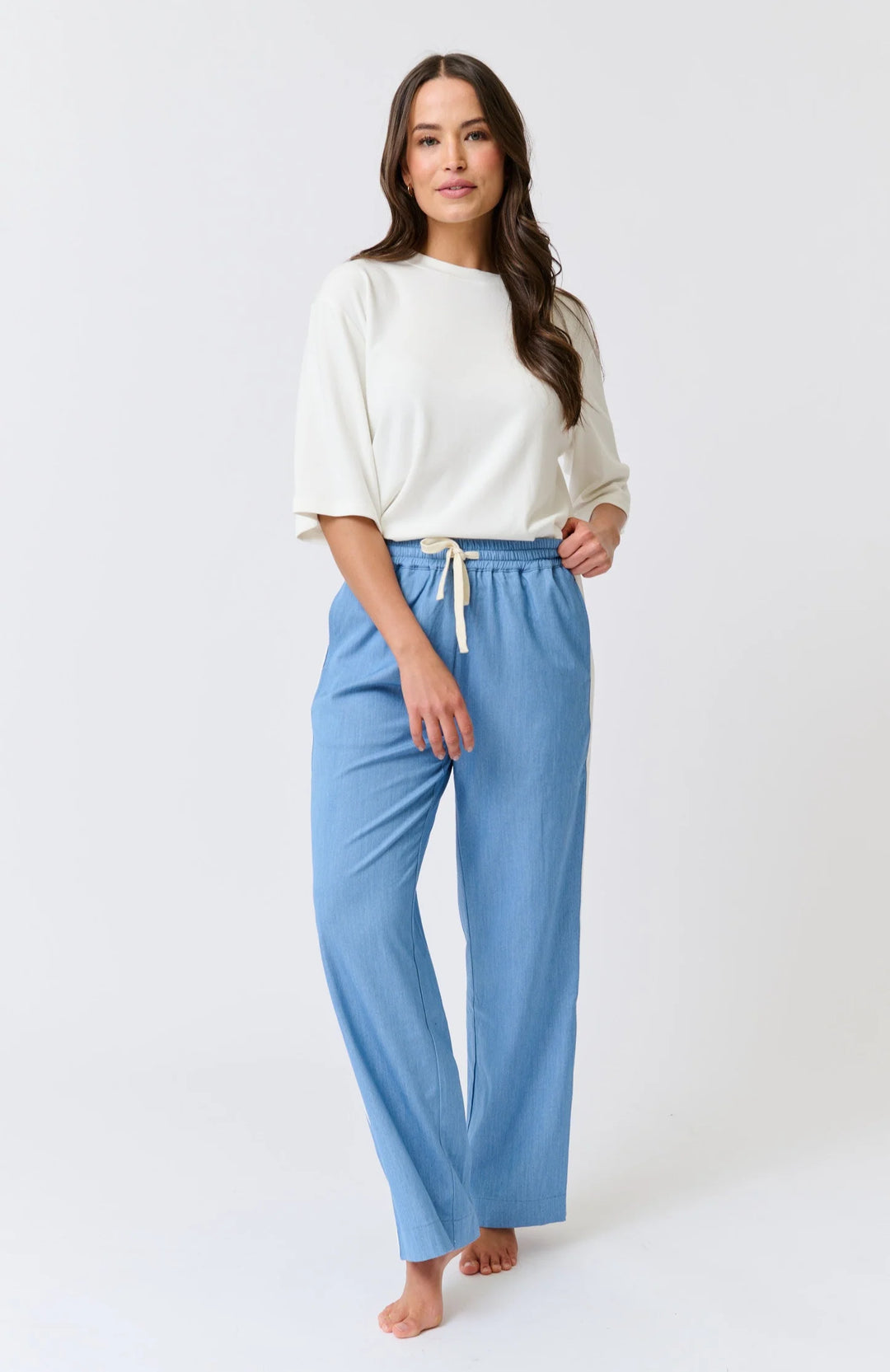 Woman wearing a white top and blue pants on a white background