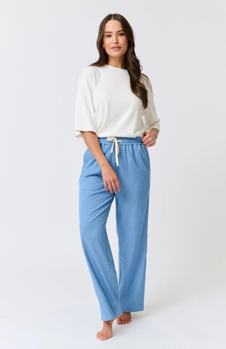 Woman wearing a white top and blue pants on a white background