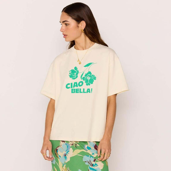 Woman wearing a cream t-shirt with green text and a green floral skirt on a white background