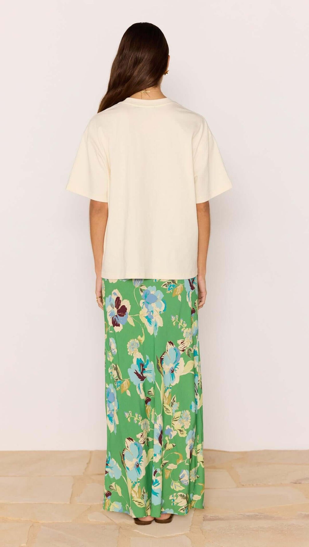 Person wearing a cream top and green floral pants on a plain background