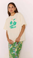 Woman wearing a cream t-shirt with green text and floral design, standing against a white background
