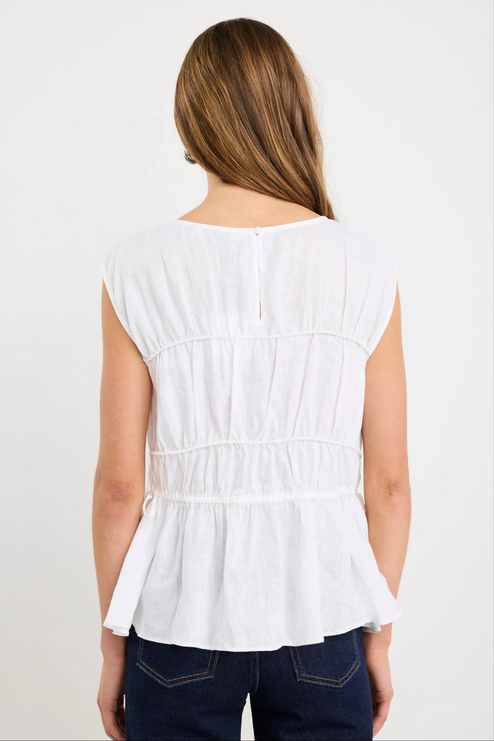 Woman wearing a white sleeveless top with a plain background