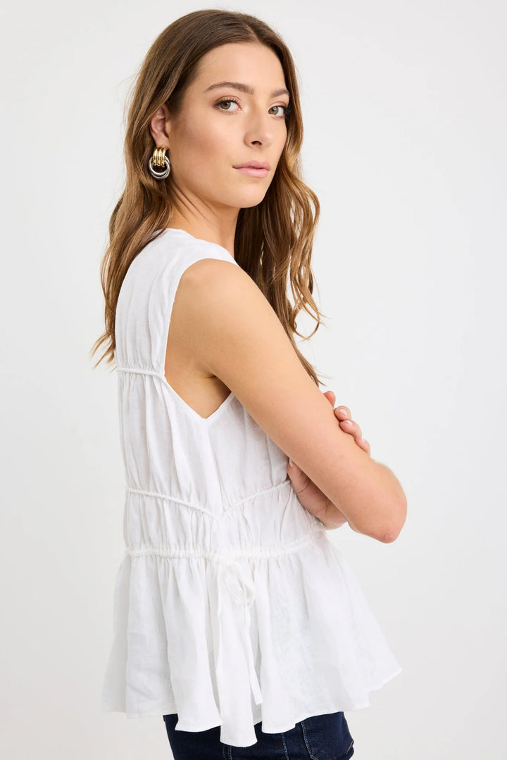 Woman wearing a white sleeveless top with a plain background