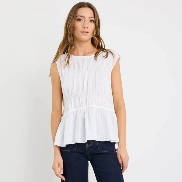 Woman wearing a white sleeveless top and dark blue jeans on a white background