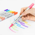 Hand holding a pink marker with colorful markers on a white background