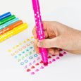Hand holding a pink marker with colorful markers and decorated paper in the background
