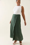 Woman wearing a white top and green isle of mine skirt on a plain background