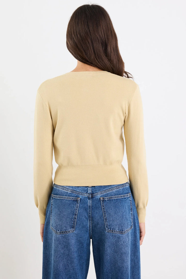 Person wearing a beige sweater and blue jeans on a white background