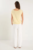 Woman wearing a yellow top and white pants on a white background