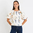 Woman wearing a floral blouse and blue jeans on a white background