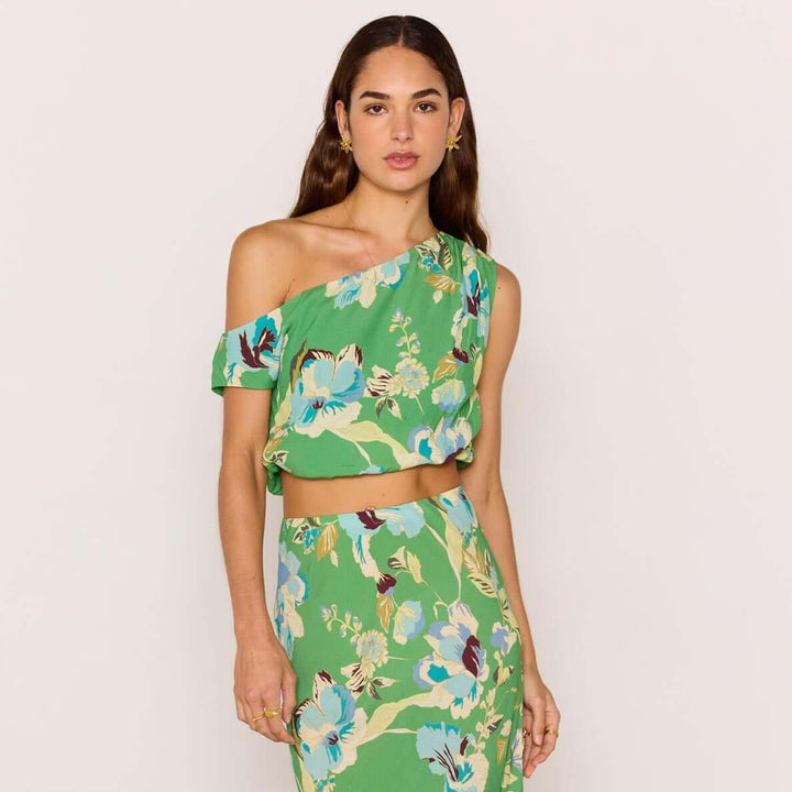 Woman wearing a green floral off-shoulder top and skirt set against a white background.