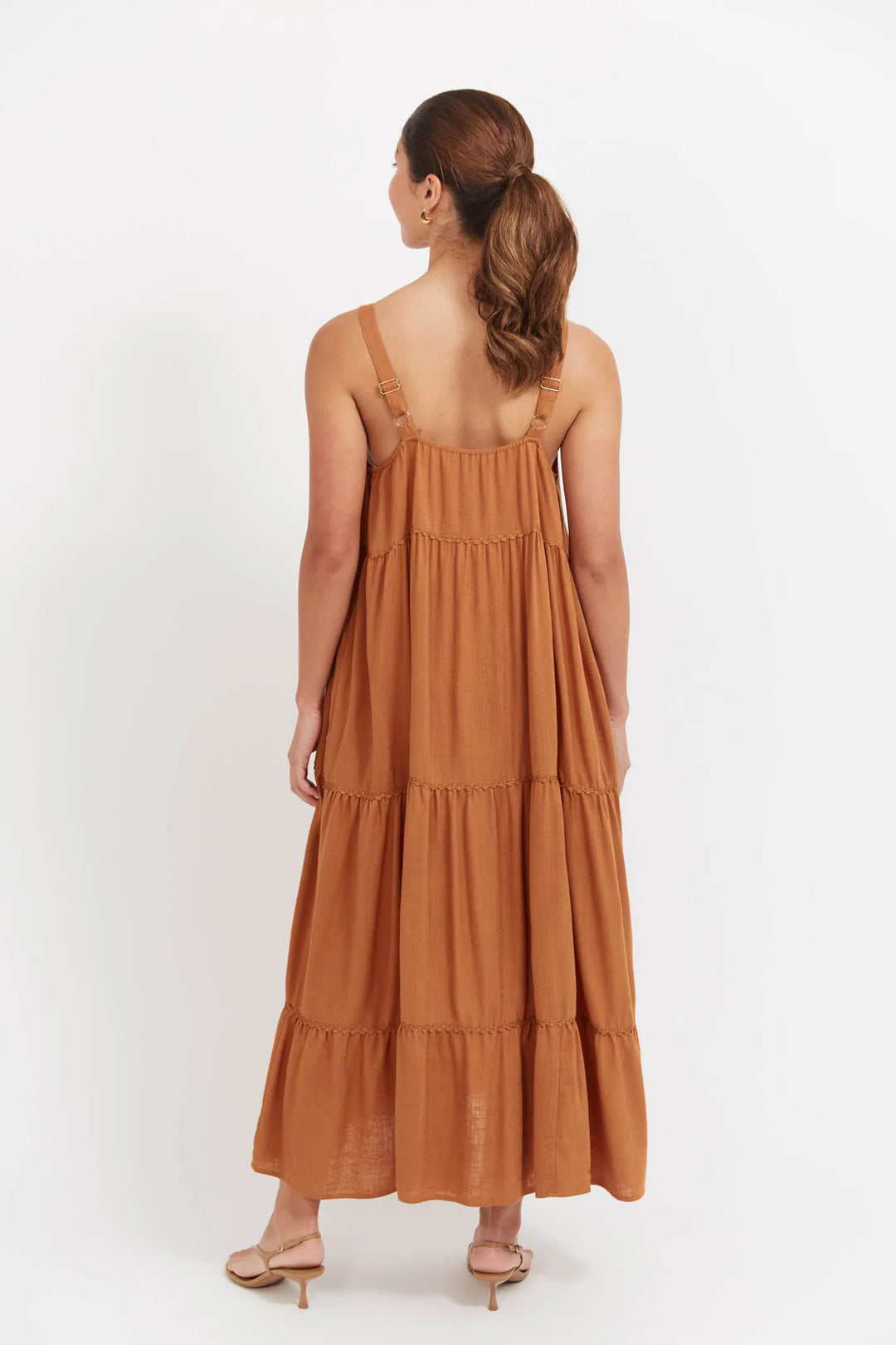 Woman wearing a Haven brown tiered dress on a white background