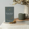 Hemp Relief tea box with a mug and dried herbs on a table