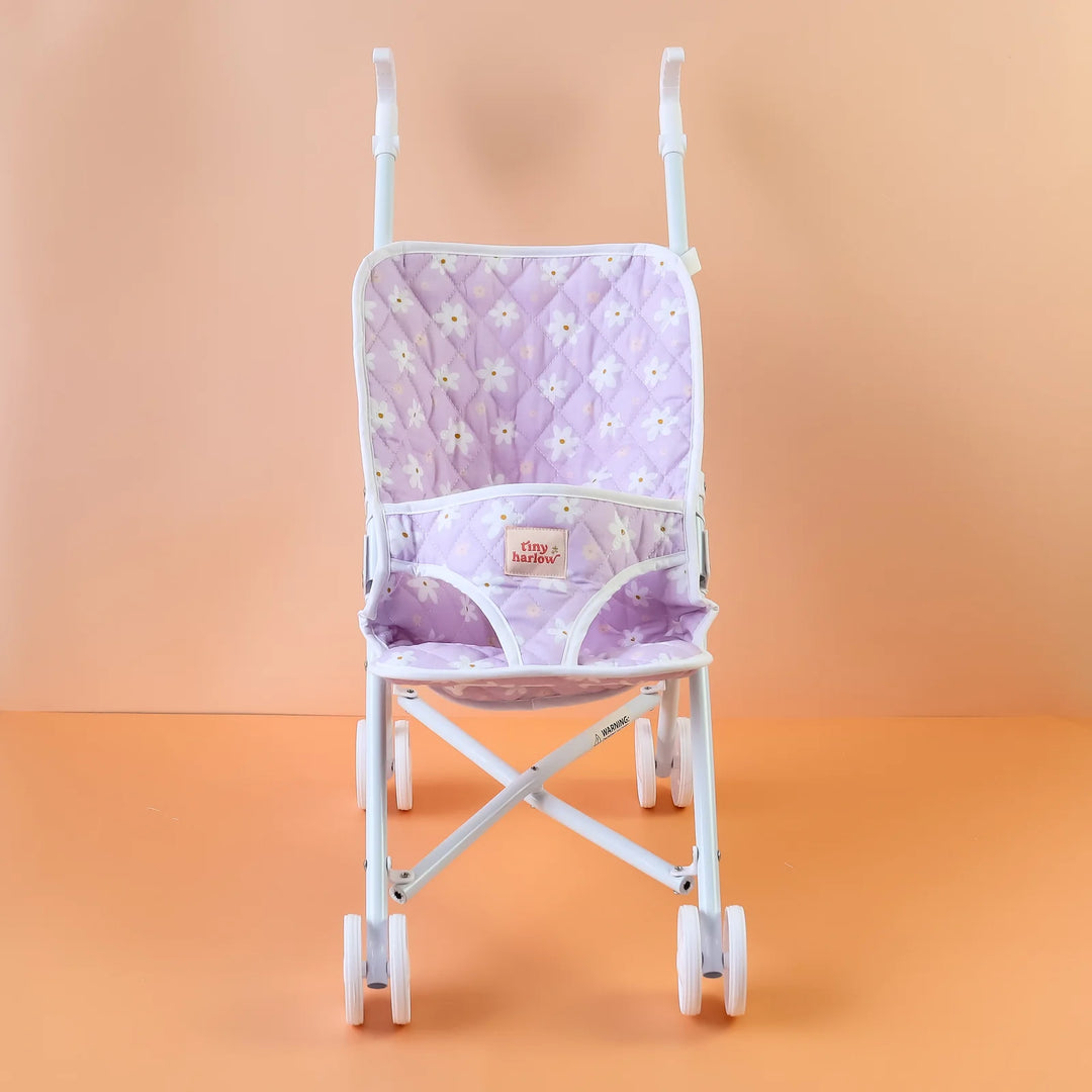 Tiny Harlow Purple floral-patterned dolls stroller against an orange gradient background