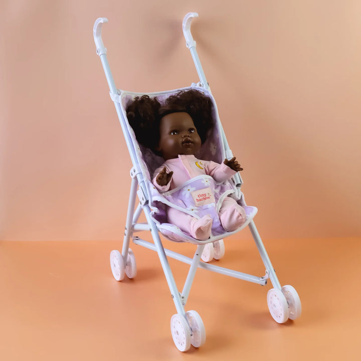Tiny Harlow Purple floral-patterned dolls stroller against an orange gradient background