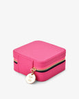 Pink jewelry box with gold zipper and round tag on a white background