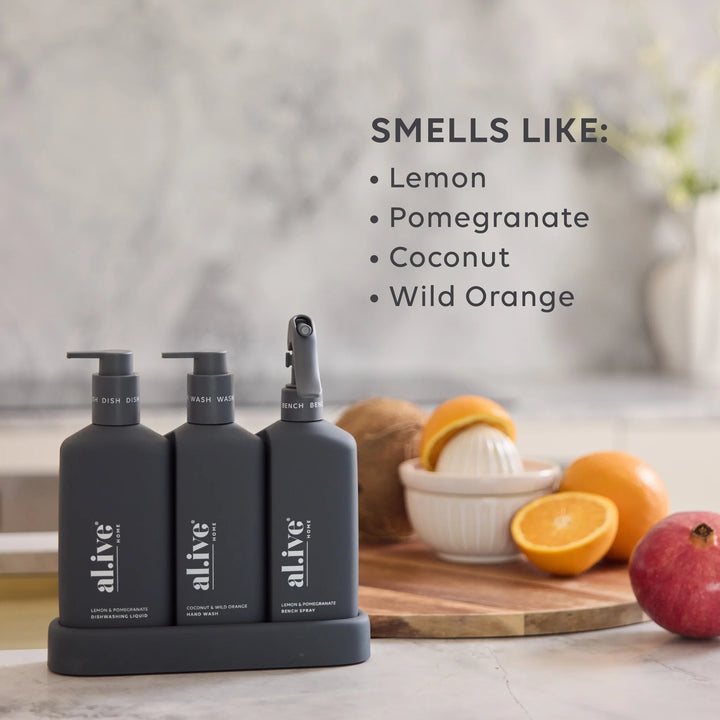 Three black bottles labeled 'alive' with pump dispensers on a kitchen counter, surrounded by fruits.