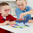 Two children playing with a colorful shark-shaped toy on a table.