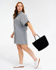 Woman wearing a gray dress holding a black bag on a white background