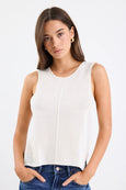 Woman wearing a white sleeveless top against a plain background