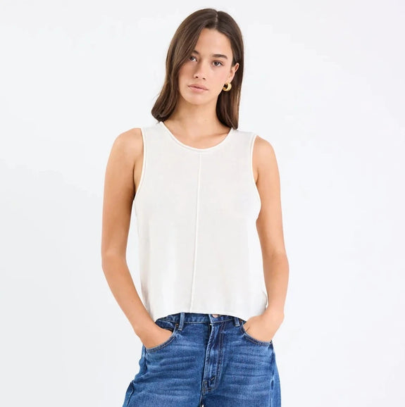 Woman wearing a white sleeveless top and blue jeans on a white background