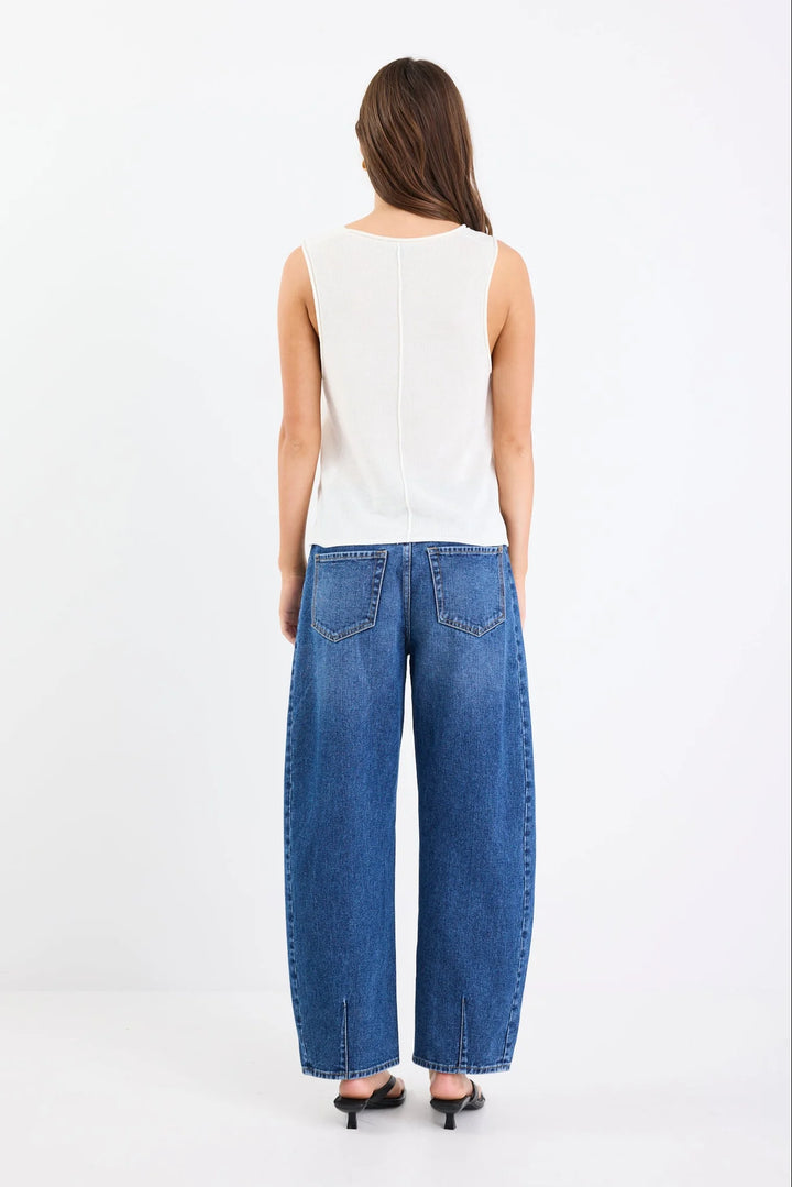 Woman wearing a white sleeveless top and blue jeans on a white background