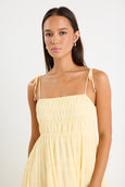 Woman wearing a light yellow dress with thin straps on a white background