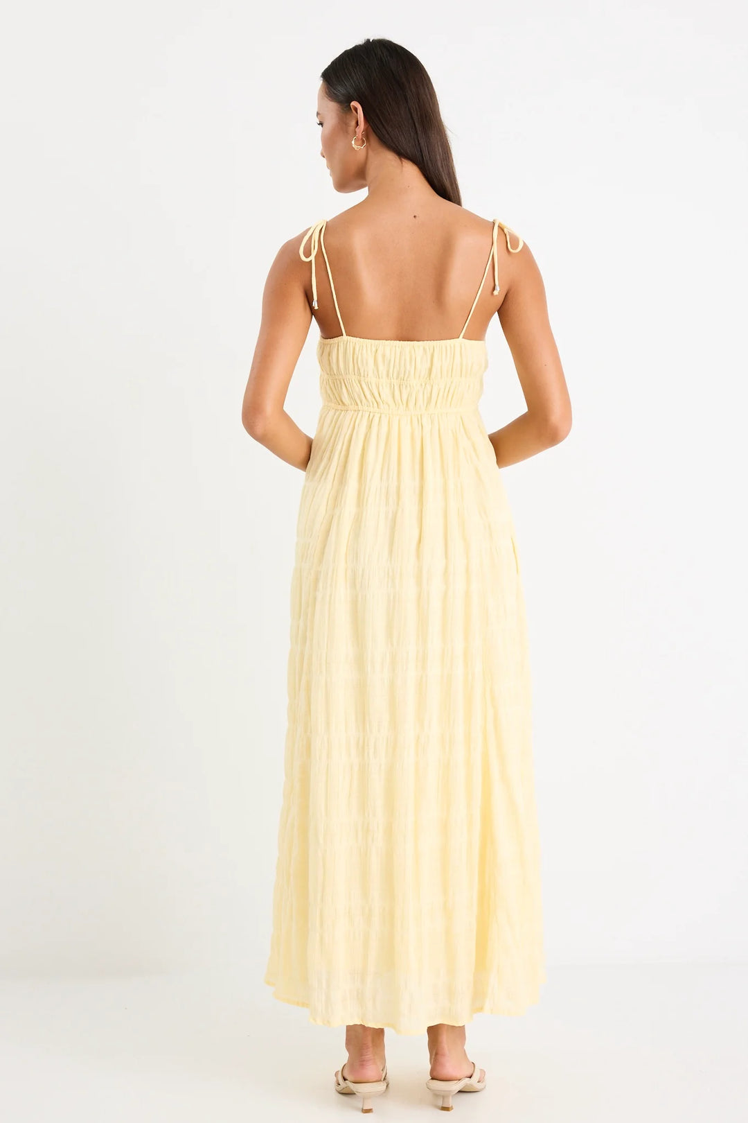 Woman wearing a yellow dress with thin straps on a white background