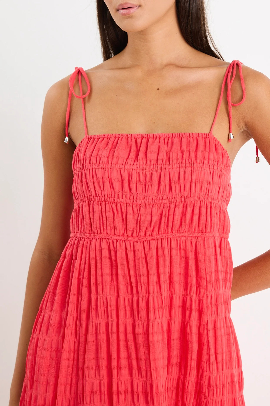 Red dress with thin straps worn by a person on a white background