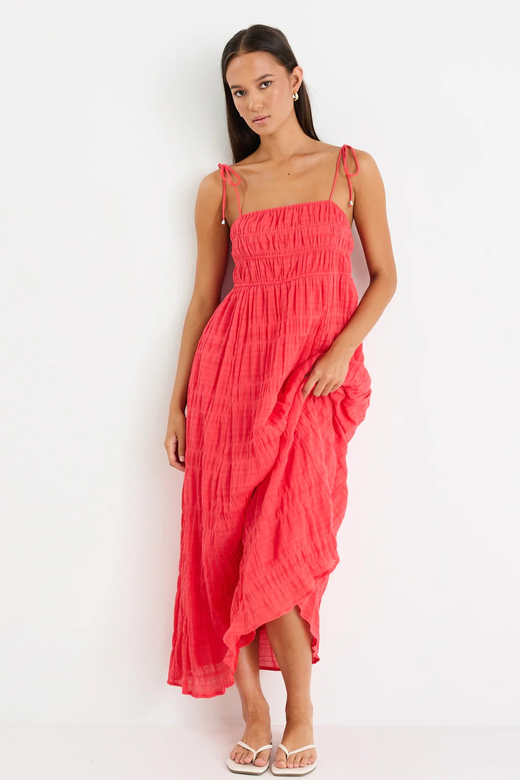 Woman wearing a coral pink dress against a white background
