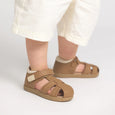 Brown sandals worn by a child on a light gray background
