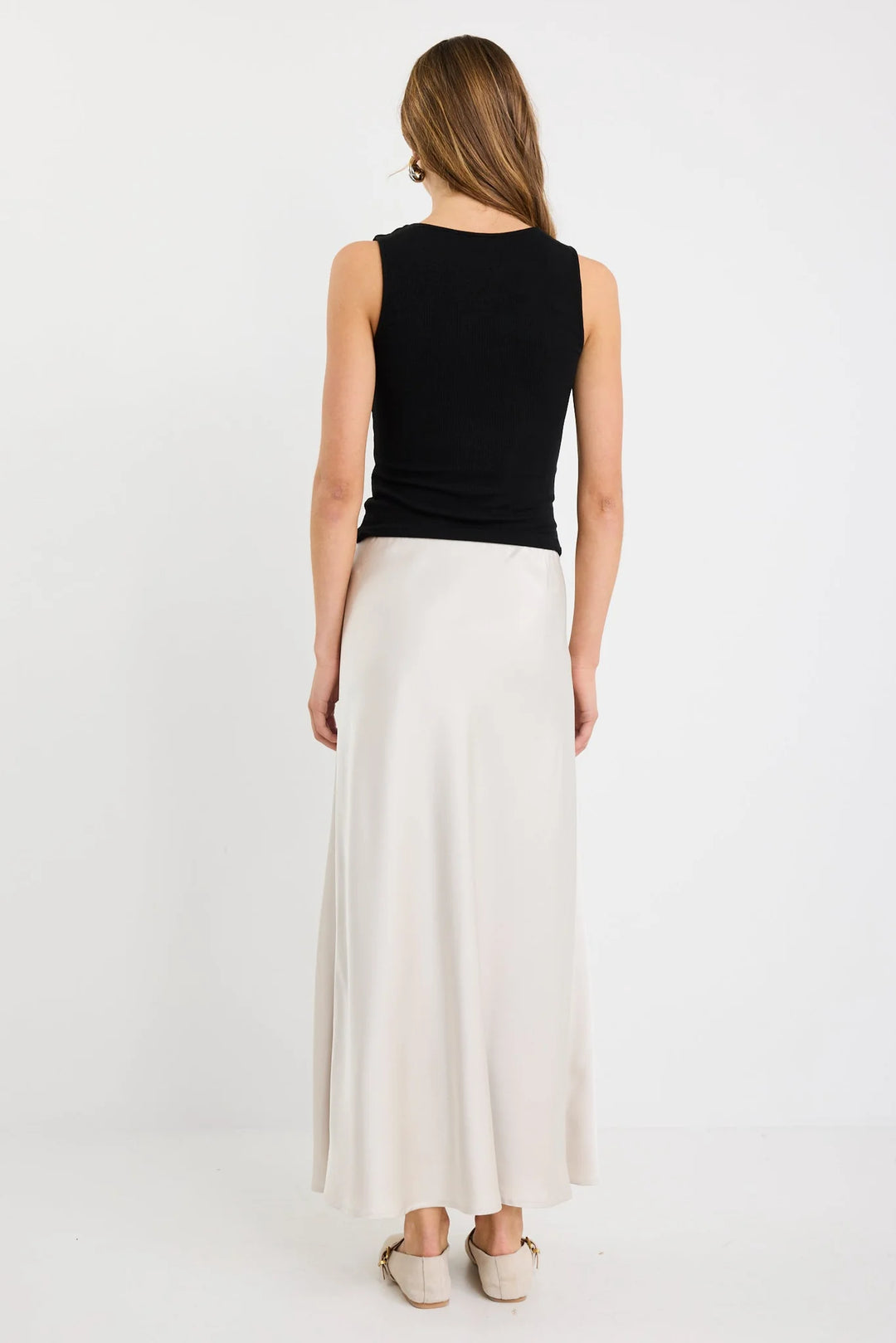 Woman wearing a black sleeveless top and white skirt on a white background