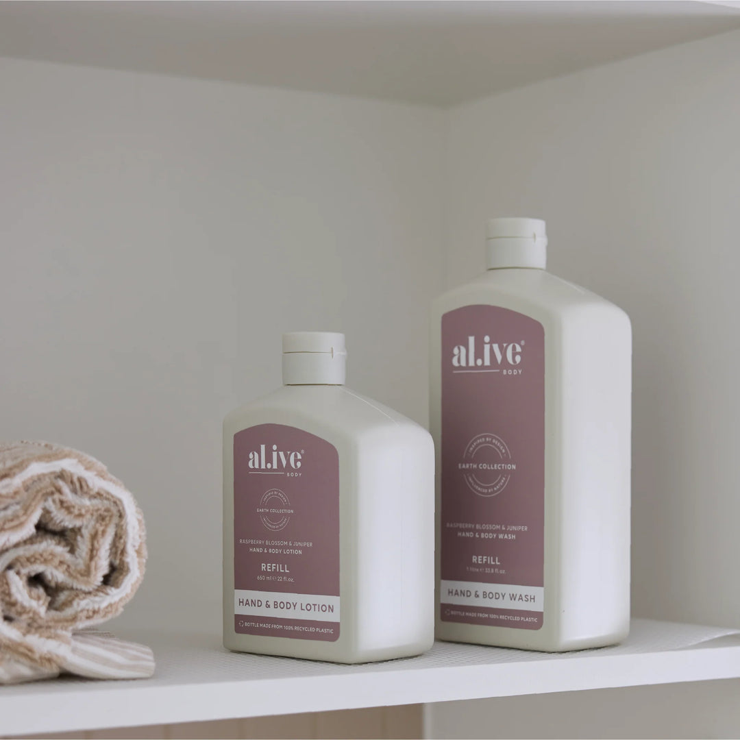 Two bottles of 'aLive' hand and body products on a shelf with a towel.