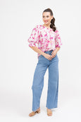 Woman wearing a pink floral blouse and blue jeans on a white background