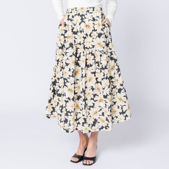 Woman wearing a floral skirt and white top on a white background