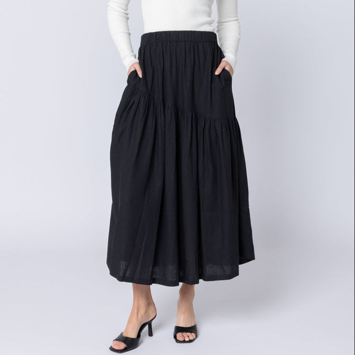 Woman wearing a white off-shoulder top and black skirt on a white background