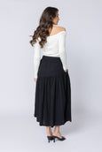 Woman wearing a white off-shoulder top and black skirt on a white background