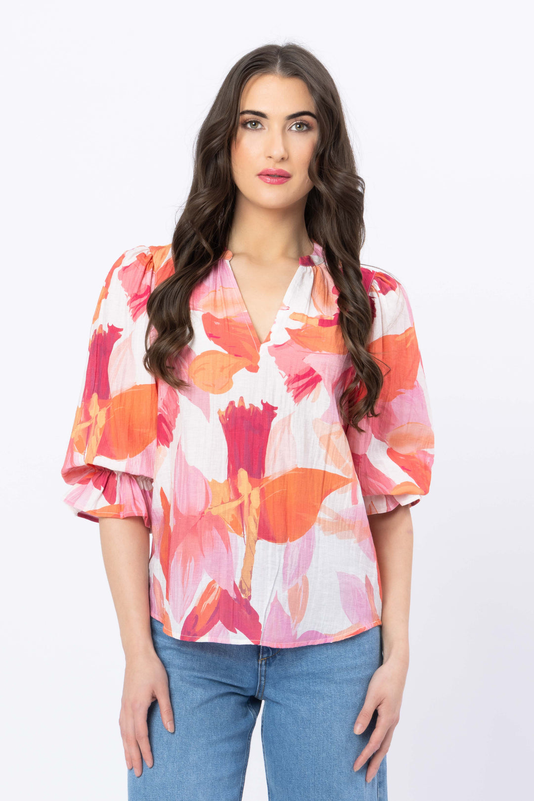 Woman wearing a colorful floral blouse with blue jeans on a white background