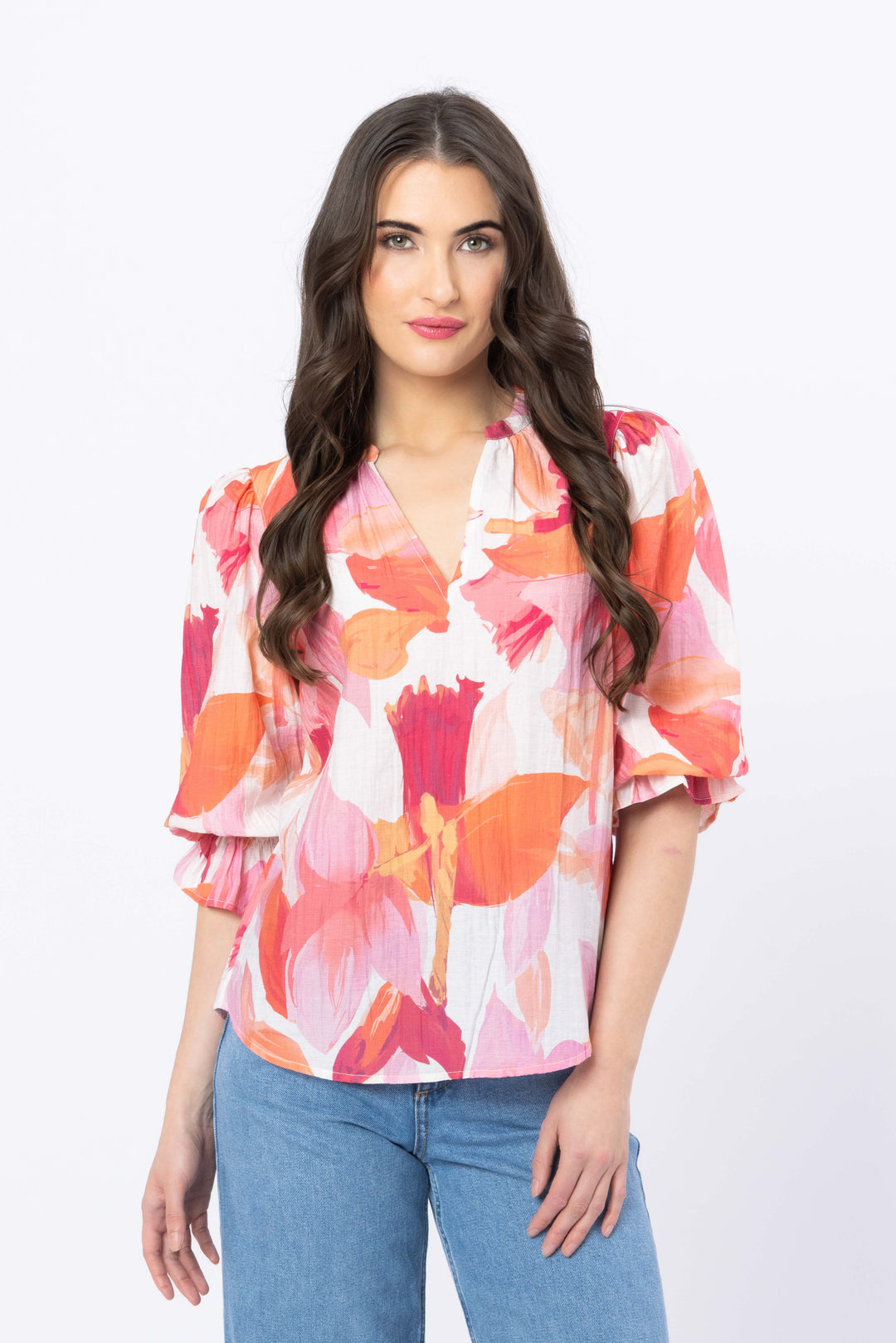 Woman wearing a colorful floral blouse with blue jeans on a white background