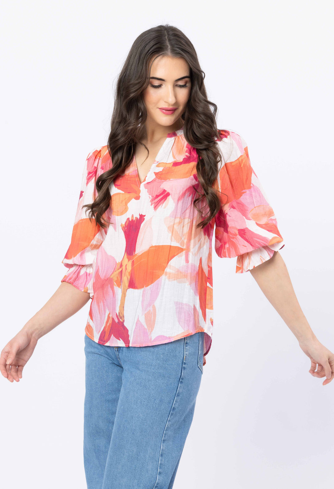 Woman wearing a colorful floral blouse with blue jeans on a white background