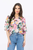 Woman wearing a colorful floral blouse and blue jeans on a white background
