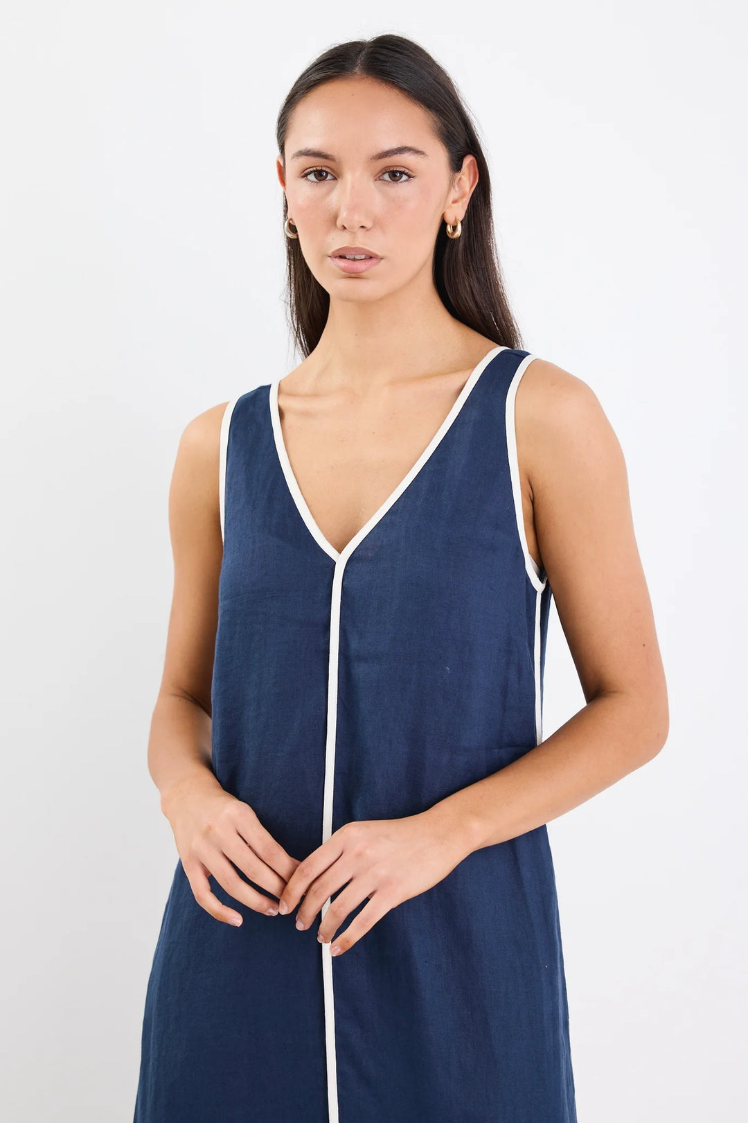 Woman wearing a navy sleeveless dress with a white zipper on a light gray background