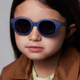 Child wearing blue sunglasses with a plain background