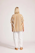 Person wearing a eb & ive striped shirt and white pants on a plain background