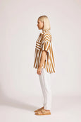 Woman wearing a eb & ive striped shirt and white pants on a plain background