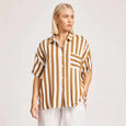 Person wearing a eb & ive striped shirt and white pants on a plain background