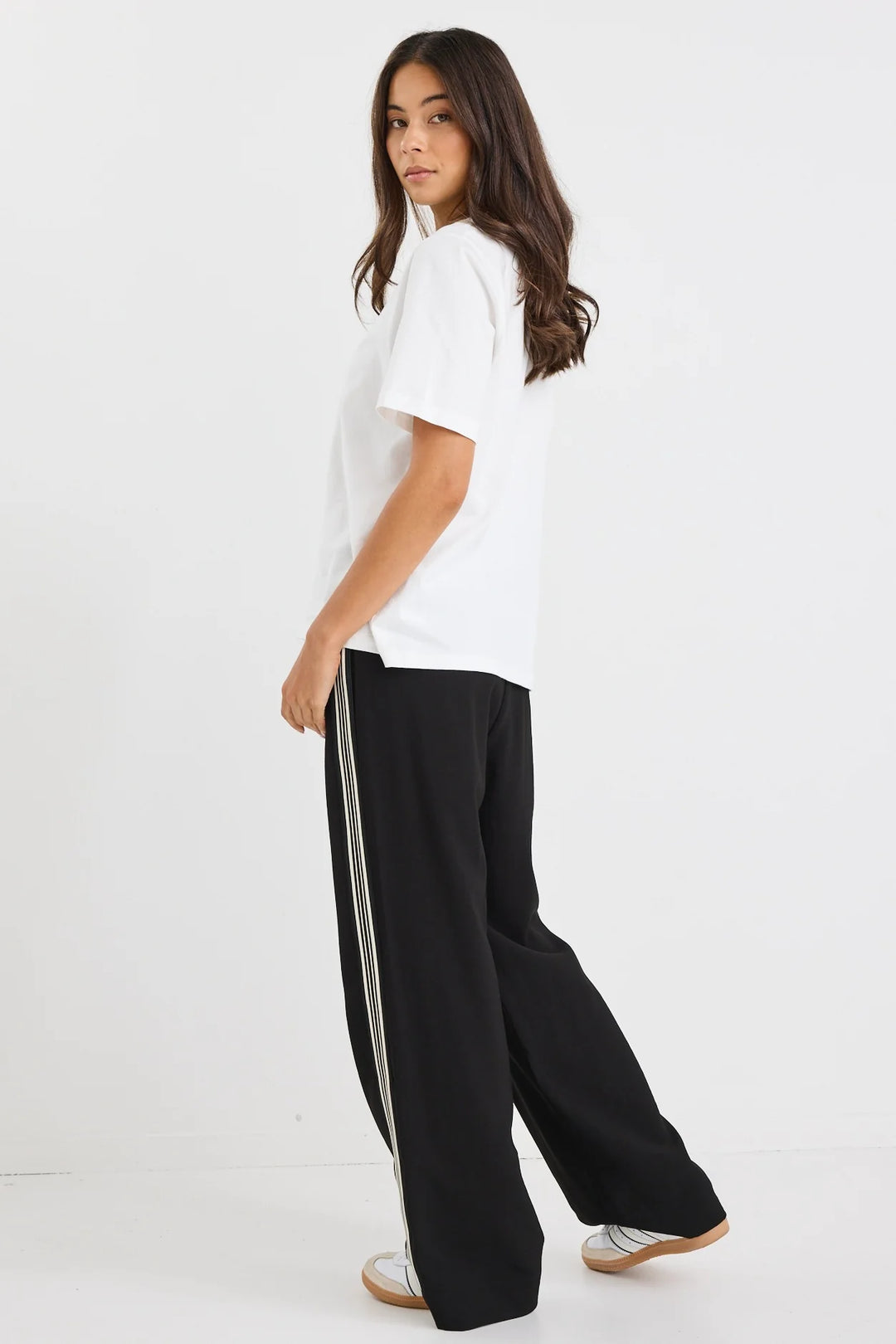 Person wearing a white t-shirt and black vibe pants with a stripe on a white background
