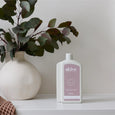 White bottle of 'alive' soap on a shelf with a vase and eucalyptus leaves in the background.