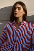 Woman wearing a red and white striped shirt against a neutral wall.
