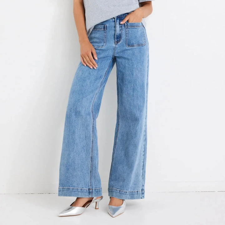 Woman wearing a gray t-shirt and blue Zoey jeans against a white background